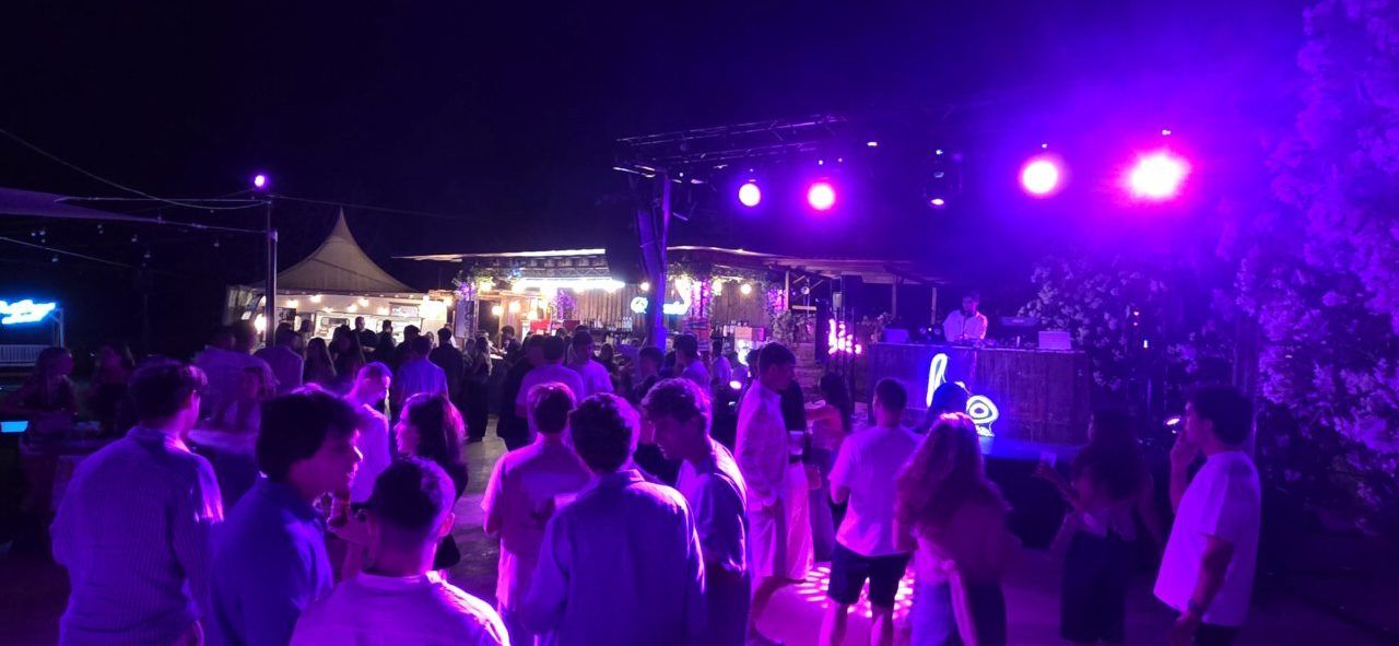 Personas bailando en una fiesta nocturna con luces de colores