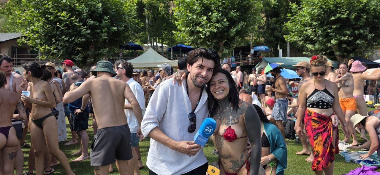 Dos personas posando en un evento de verano con una multitud de fondo