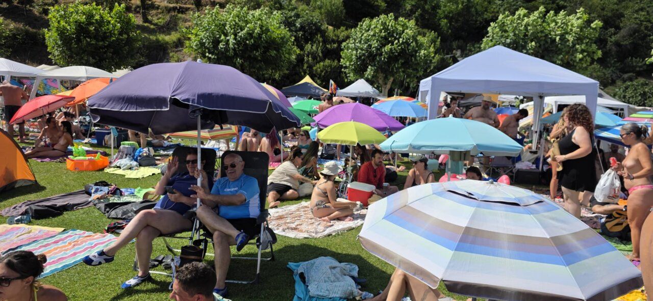 Multitud de personas disfrutando en un evento al aire libre con sombrillas