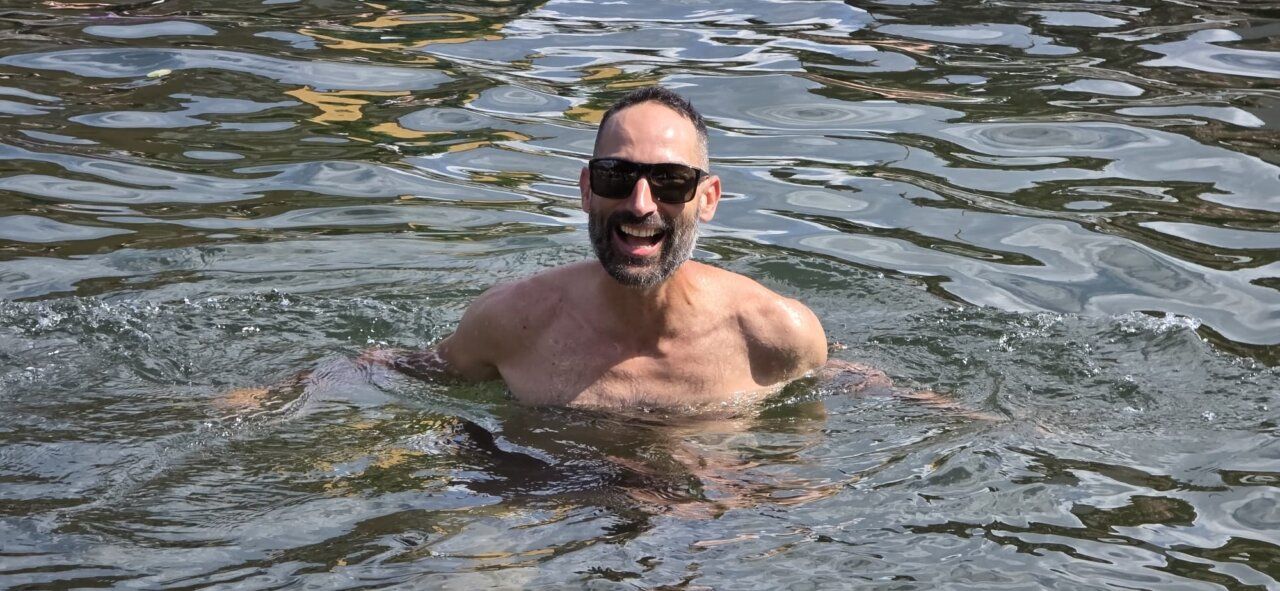 Hombre nadando en un lago con una gran sonrisa