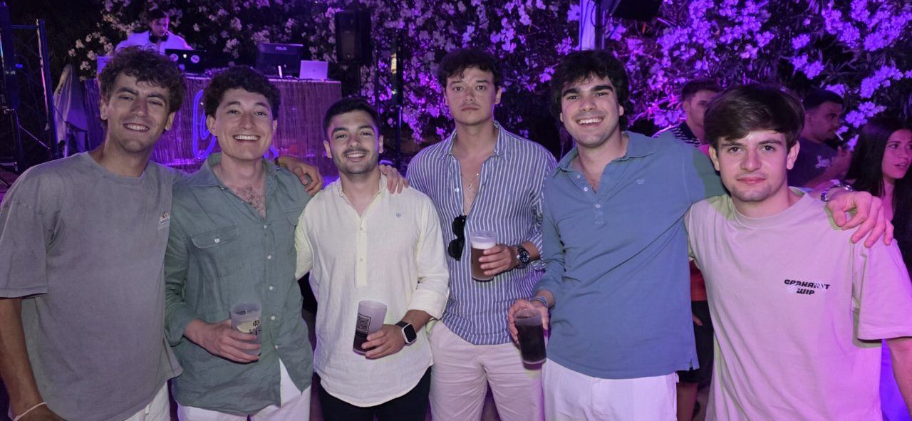 Grupo de amigos sonriendo en una fiesta nocturna con luces de colores