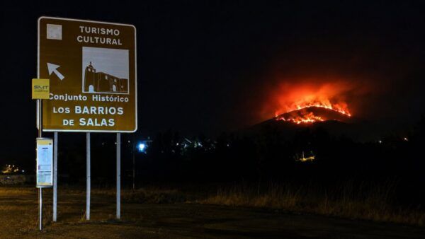 Señal de turismo cultural con incendio en el fondo en Villanueva de Valdueza