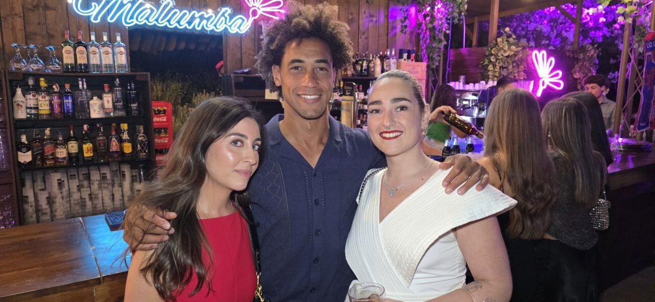 Tres personas posando en un bar con luces de neón