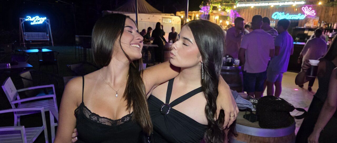 Dos amigas sonriendo y posando en una fiesta nocturna