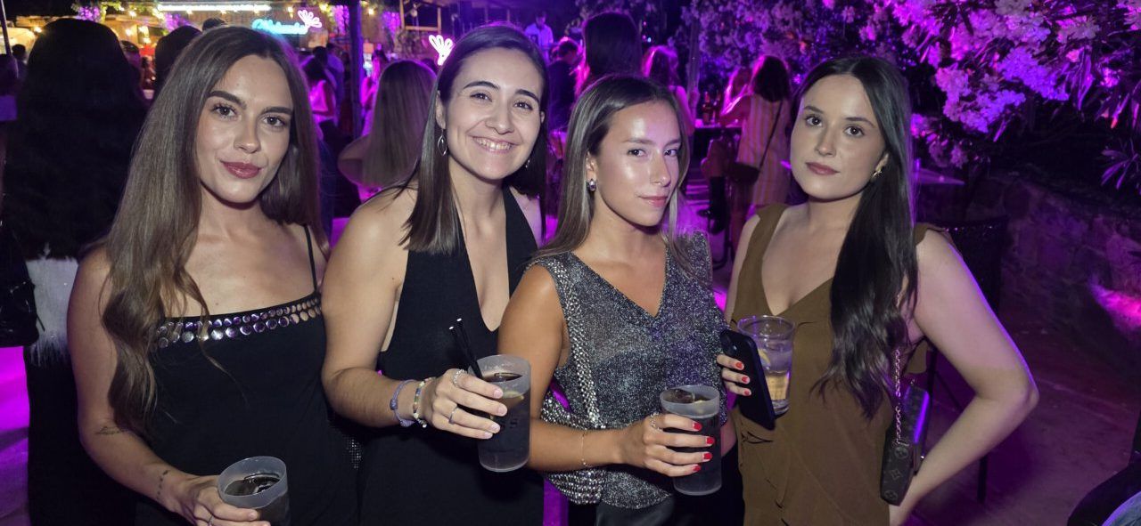 Cuatro mujeres sonriendo en una fiesta con copas en la mano