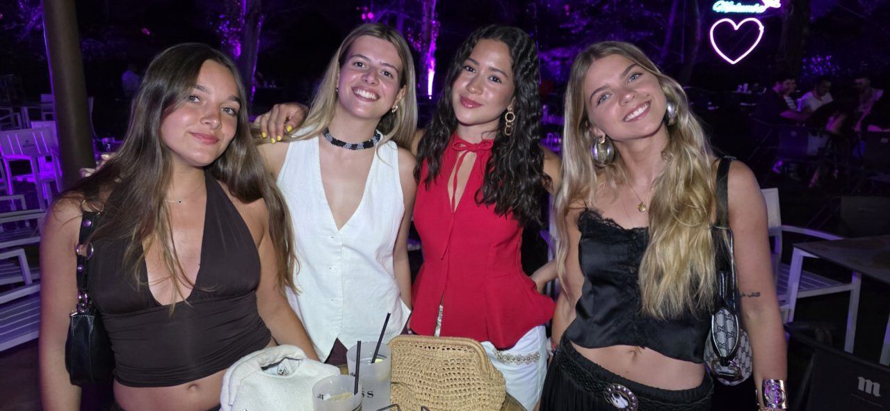Cuatro amigas posando en una fiesta con luces de colores
