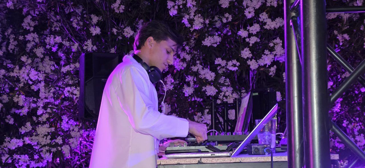 DJ actuando en un evento con fondo de flores
