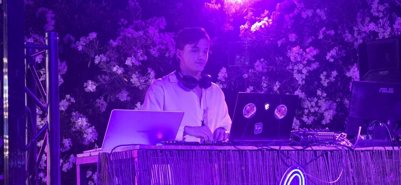 DJ Malumba actuando en un evento nocturno con luces moradas