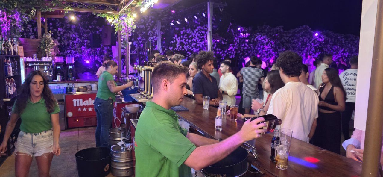 Personas disfrutando en un bar con luces de colores y bebidas