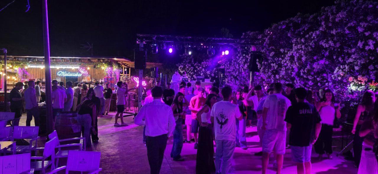 Fiesta nocturna en Malumba con luces y gente bailando
