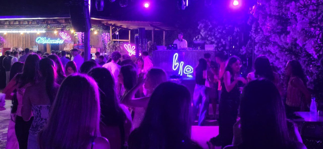Fiesta nocturna en Malumba con luces de colores y gente bailando