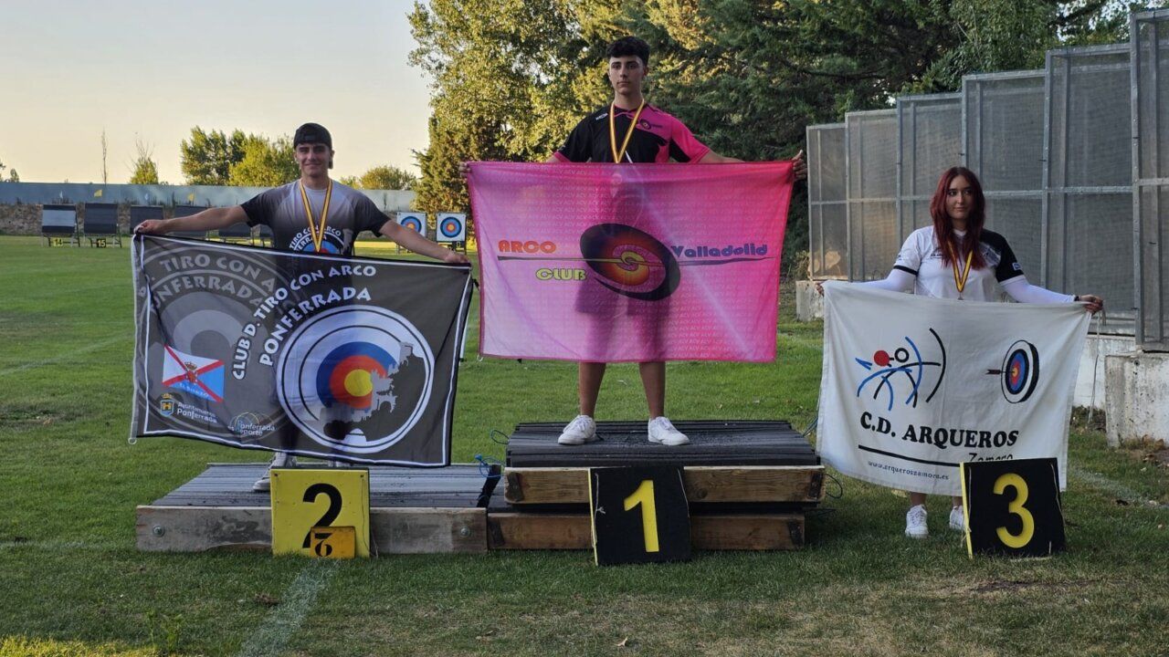 Tres arqueros en el podio con medallas y banderas del club
