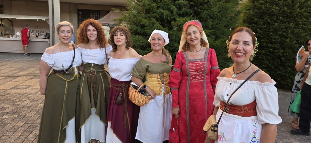 Grupo de mujeres vestidas con trajes medievales en un mercado