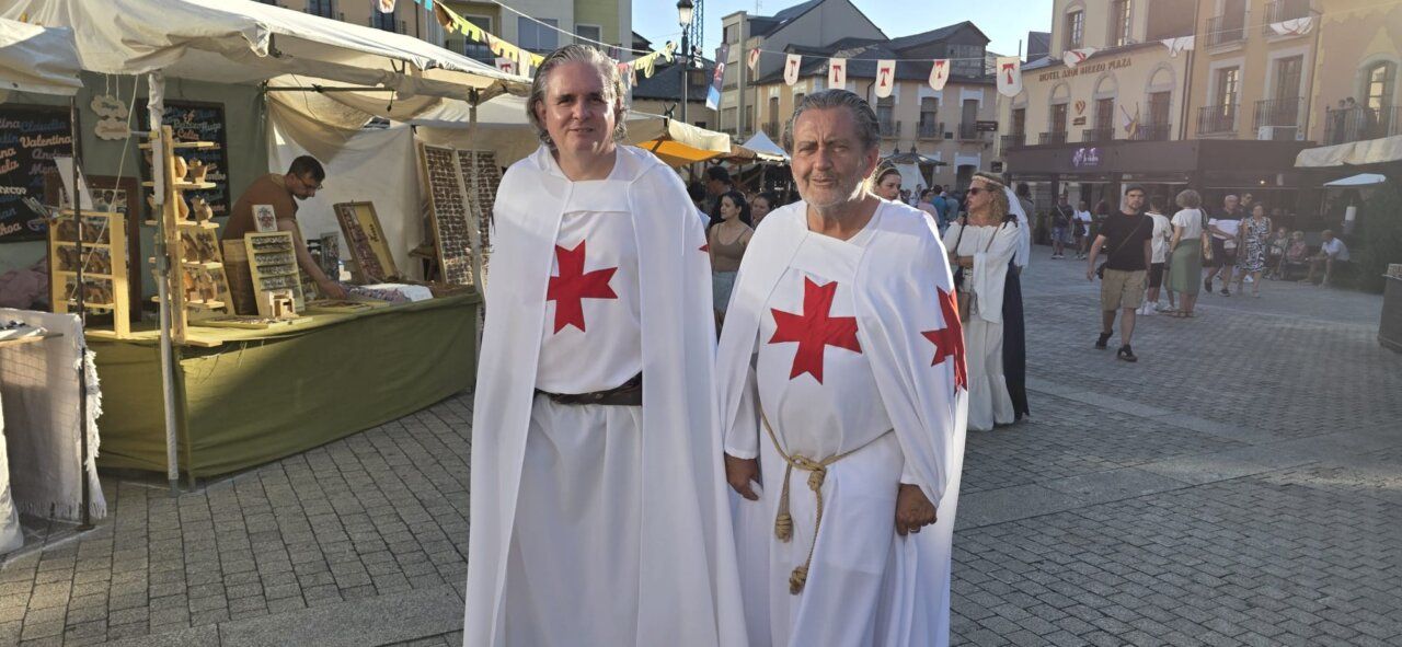 Dos hombres vestidos con túnicas medievales en un mercado