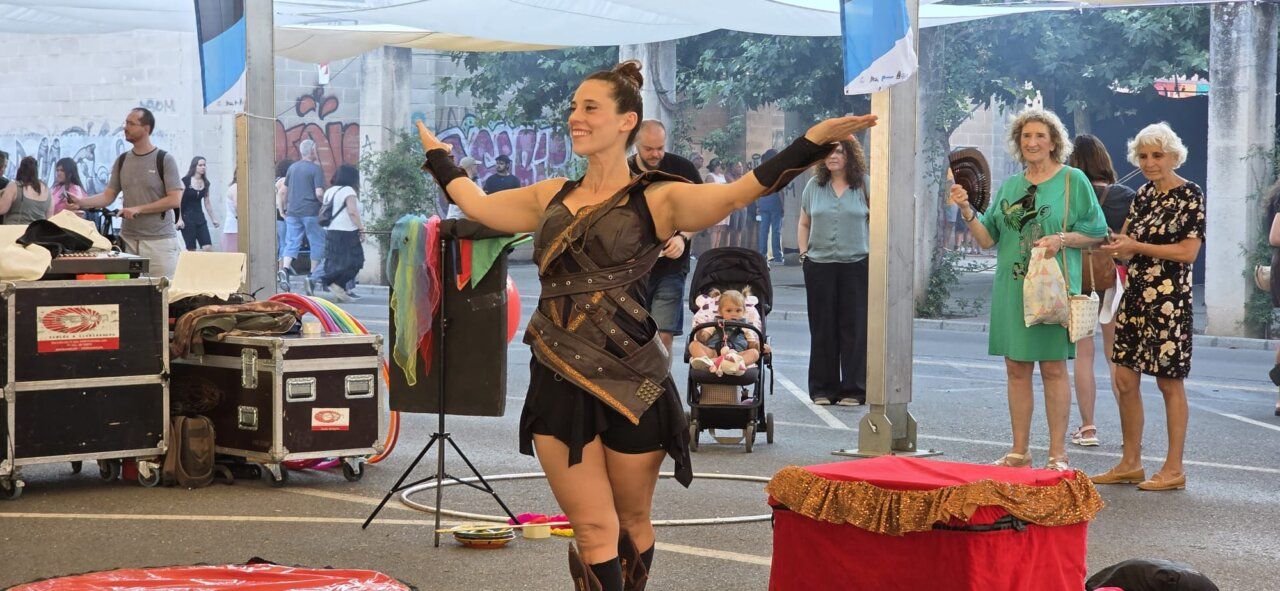 Artista de circo actuando en un mercado medieval con público alrededor.