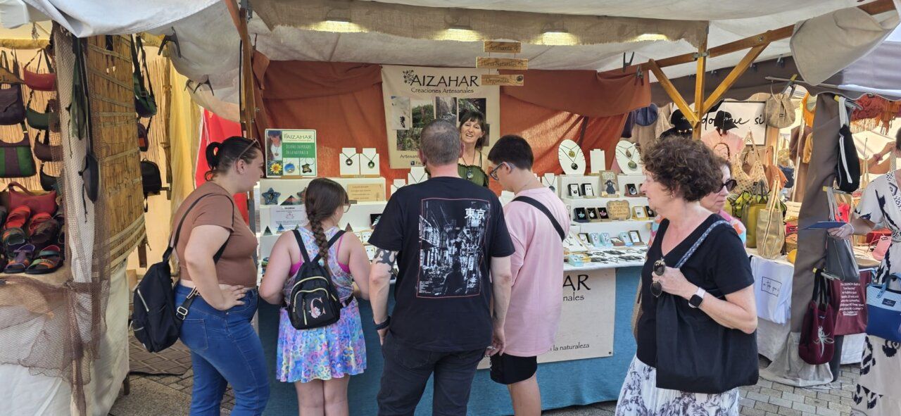 Personas visitando un puesto de artesanías en un mercado medieval
