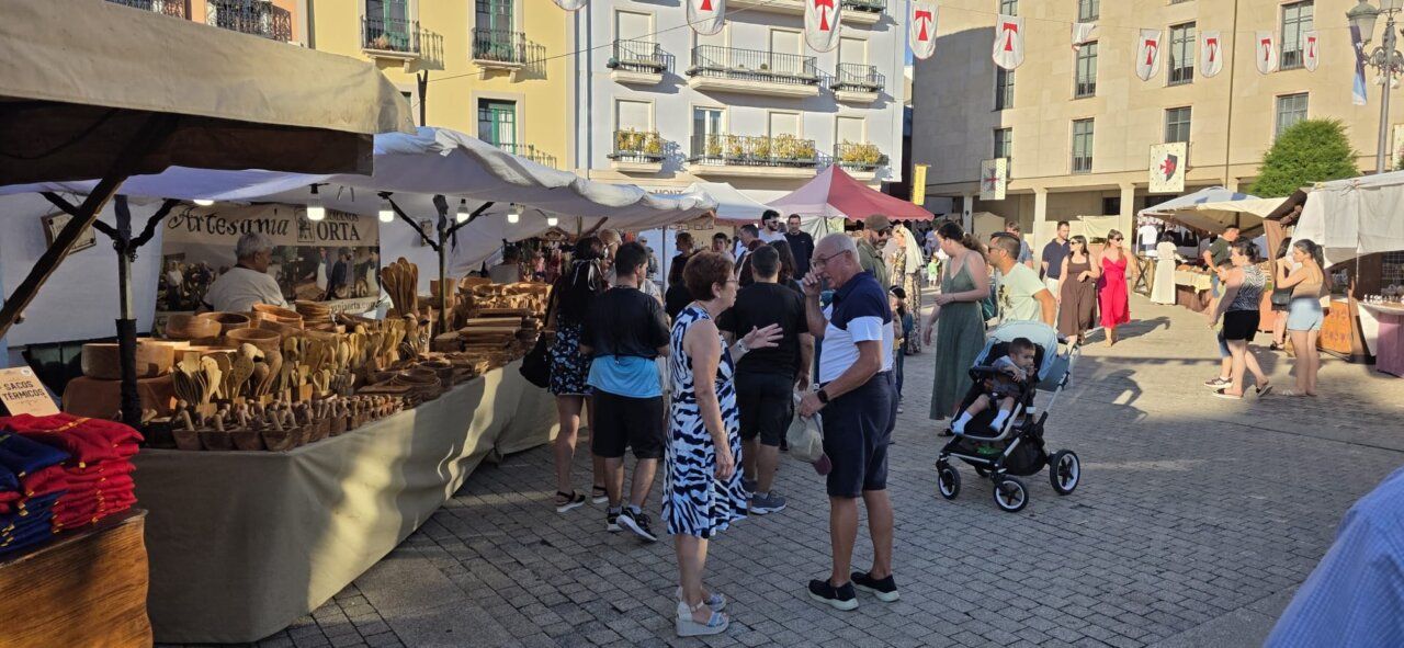 Personas en un mercado medieval con puestos de artesanía