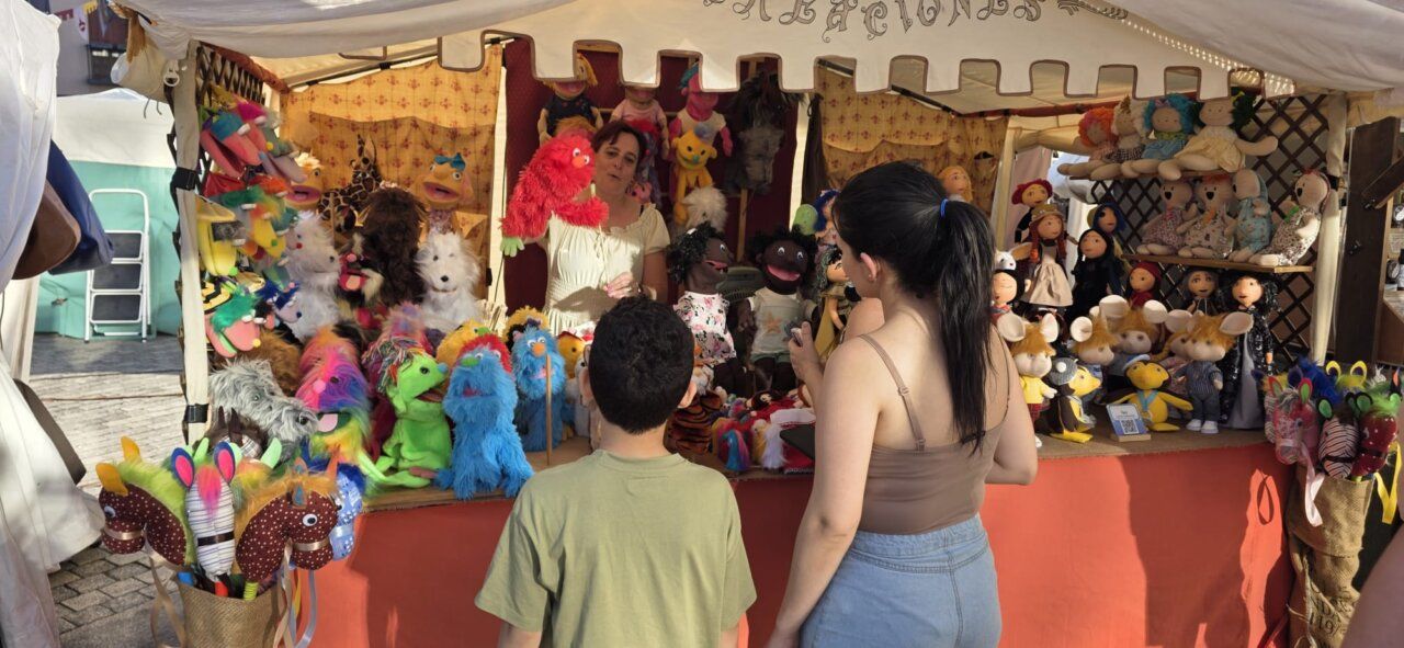 Mujer mostrando marionetas coloridas en un mercado medieval