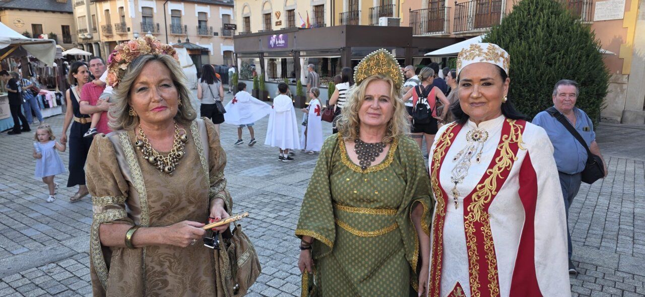 Tres mujeres vestidas con trajes medievales en un mercado