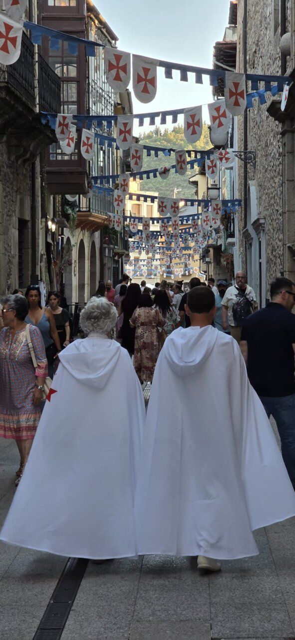Personas caminando en un mercado medieval con banderas decorativas
