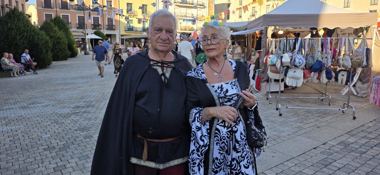 Pareja de personas vestidas con trajes medievales en un mercado