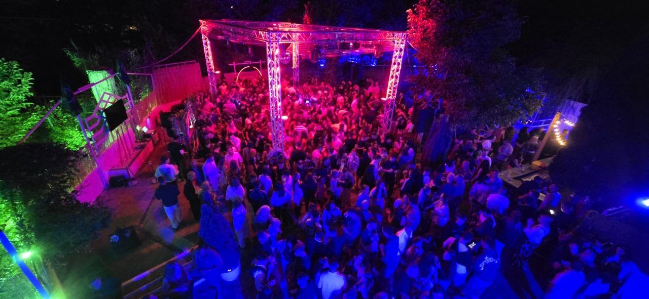 Multitud disfrutando en La Mala Vida Terrace Club con luces de colores