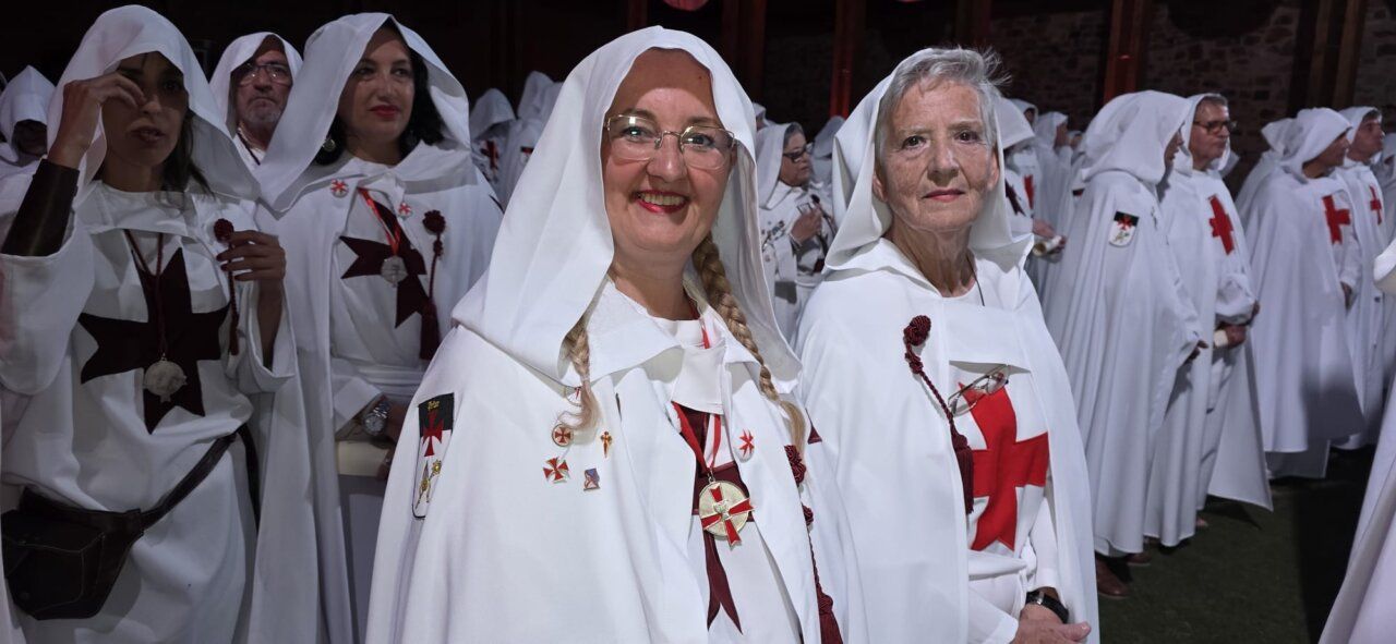 Participantes en la ceremonia de ordenación templaria con vestimenta blanca y cruces rojas.