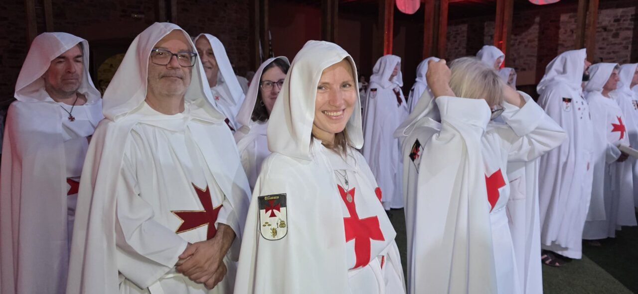 Grupo de personas vestidas con túnicas blancas y cruces rojas en ceremonia