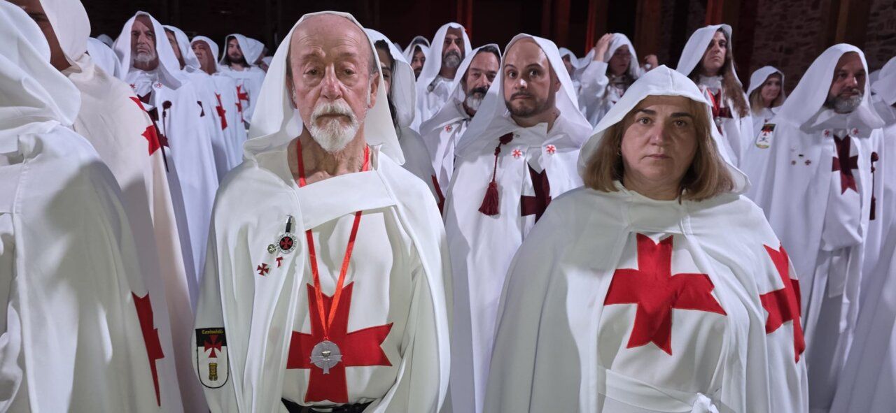 Grupo de personas vestidas con túnicas blancas y cruces rojas en una ceremonia
