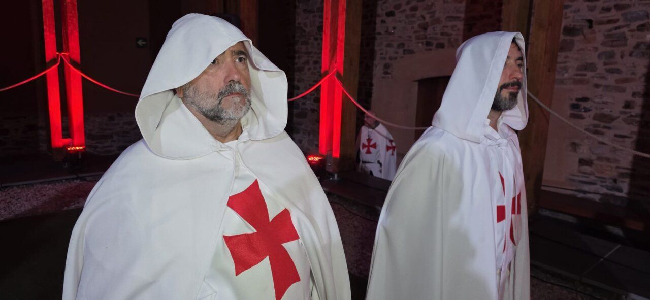 Hombres con capas blancas y cruces rojas en una ceremonia templaria