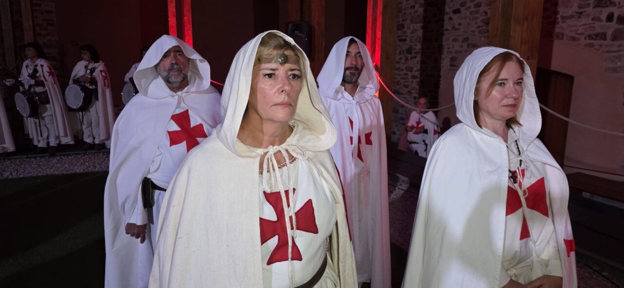 Participantes en una ceremonia de ordenación templaria con capas blancas y cruces rojas