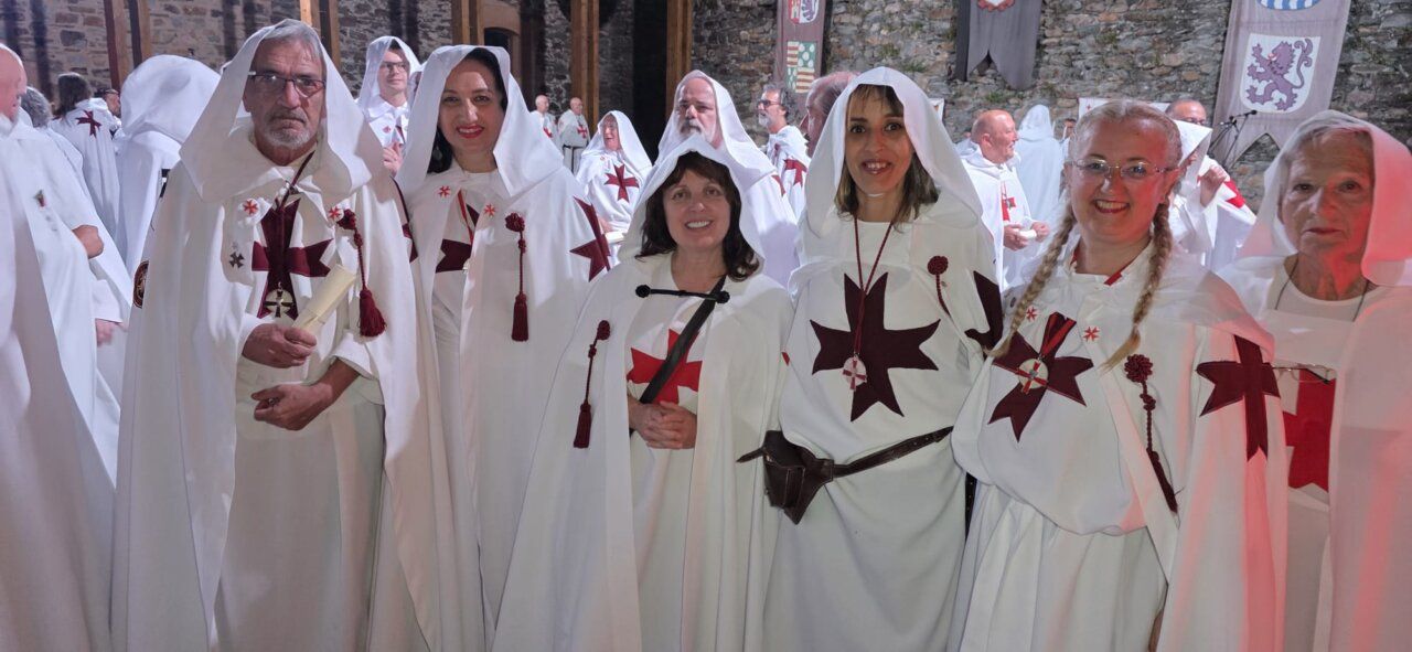 Grupo de personas vestidas con túnicas blancas y cruces rojas en ceremonia templaria