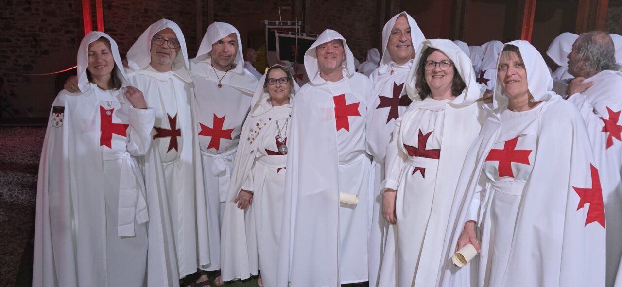 Grupo de personas vestidas con túnicas blancas y cruces rojas en una ceremonia