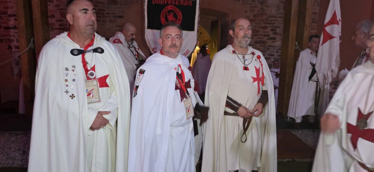Hombres con capas blancas y cruces rojas en ceremonia templaria
