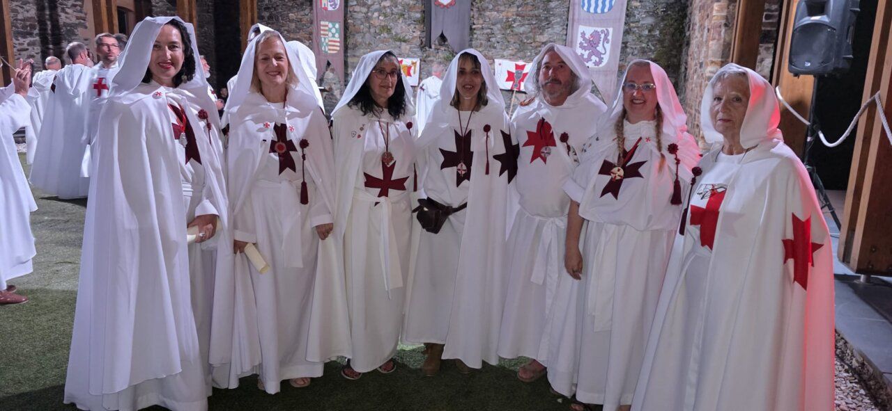 Grupo de personas vestidas con túnicas blancas y cruces rojas en ceremonia templaria.