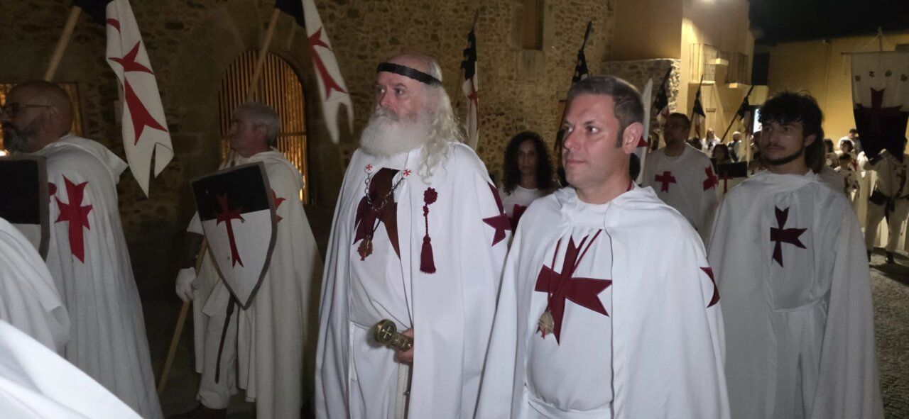 Participantes en la ceremonia de ordenación templaria con capas blancas y cruces rojas