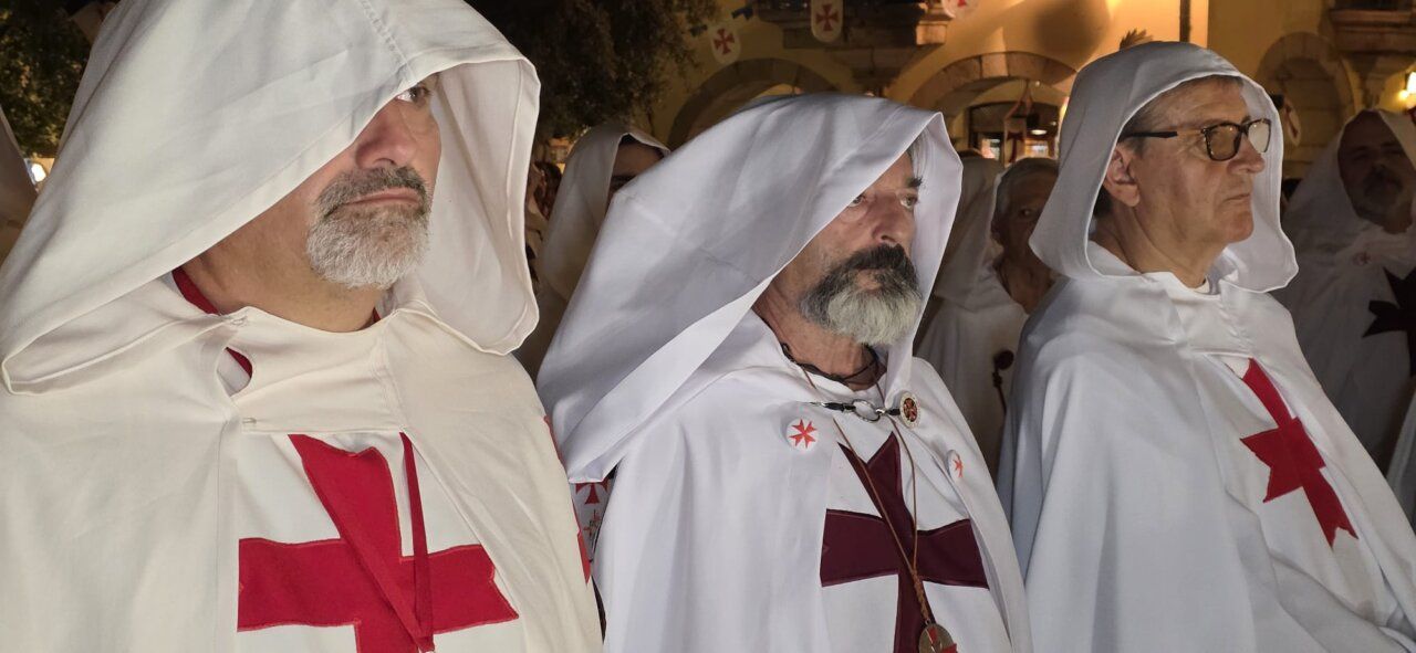 Hombres con capas blancas y cruces rojas en una ceremonia templaria