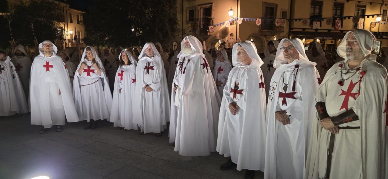 Grupo de personas con túnicas blancas y cruces rojas en una ceremonia
