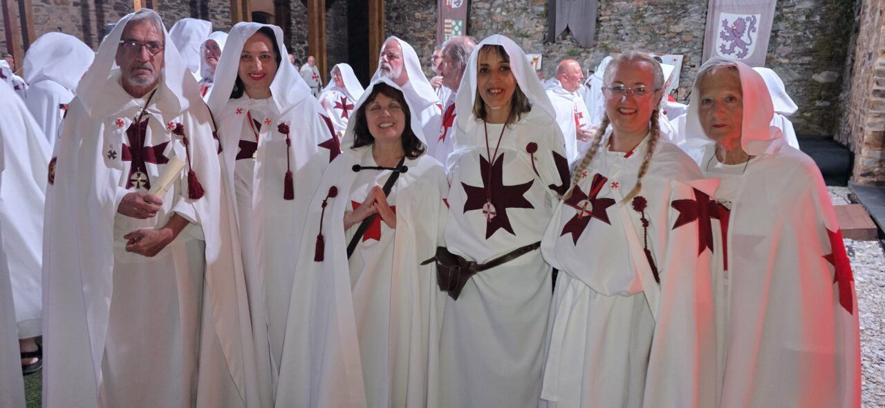 Grupo de personas con túnicas blancas y cruces rojas en ceremonia templaria.