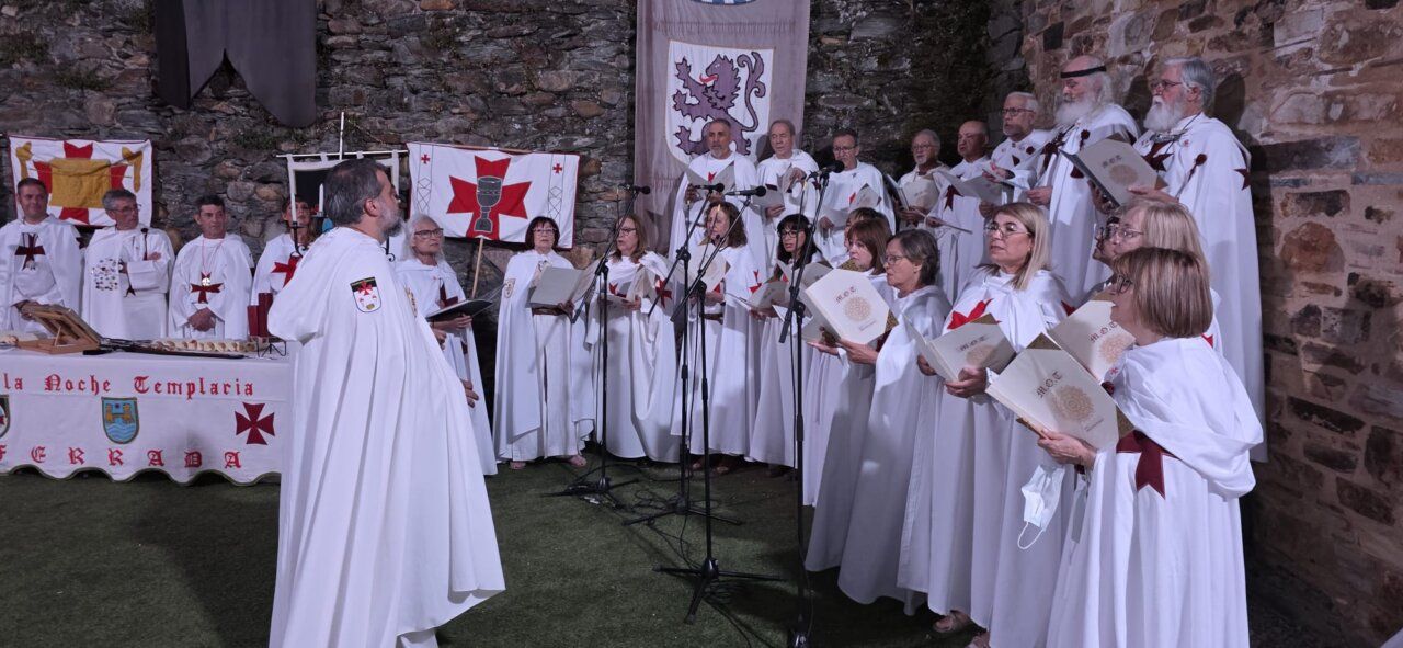 Grupo de personas en vestimenta templaria cantando en un evento