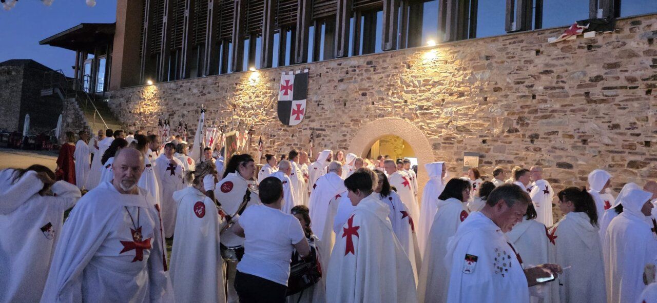 Grupo de personas con capas blancas y cruces rojas en un evento templario