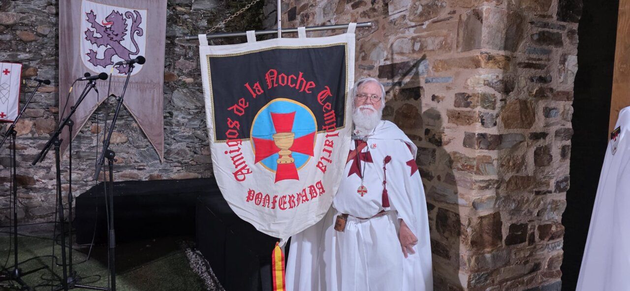 Hombre con barba blanca junto a un estandarte templario en Ponferrada