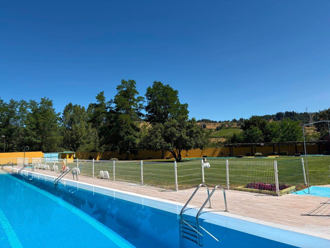 Vista de las piscinas municipales de Toreno y Matarrosa con césped y árboles
