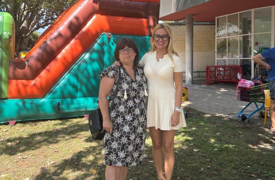 Dos mujeres posando en un taller de verano inclusivo con un tobogán inflable de fondo