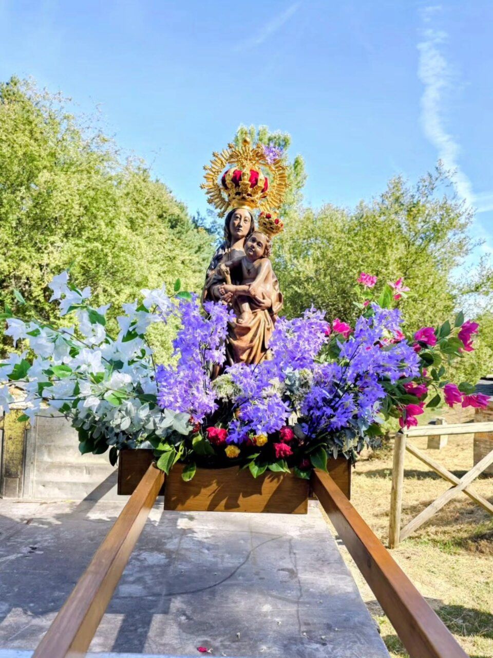 Estatua de la Virgen de la Aquiana rodeada de flores en la romería