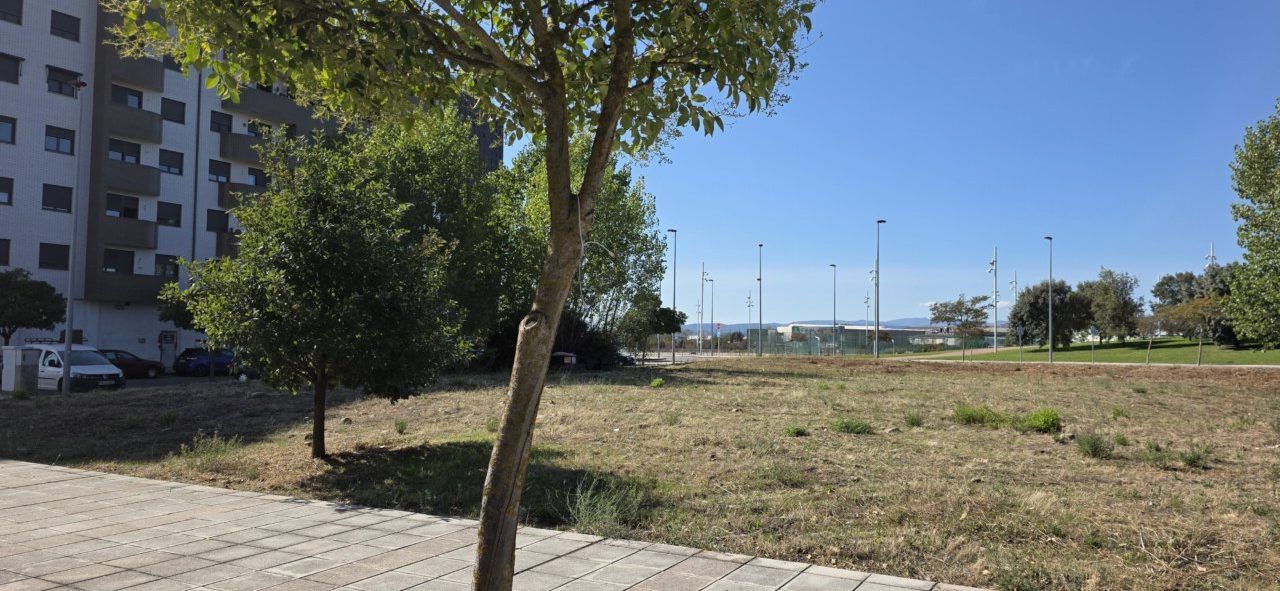 Parcela en Ponferrada destinada a viviendas de protección pública con árboles y edificios cercanos.
