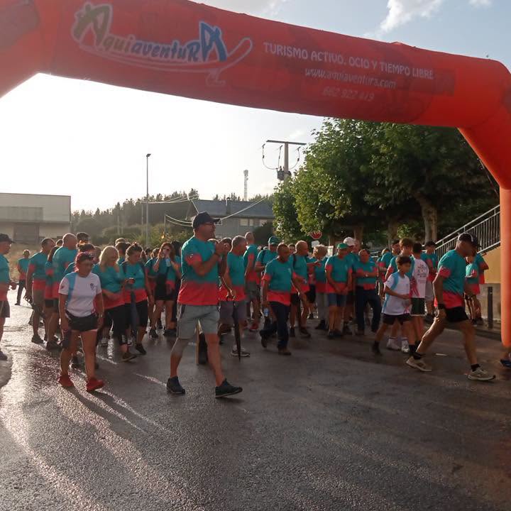 Participantes de la XXI Marcha Nocturna en Arganza bajo un arco de inicio.