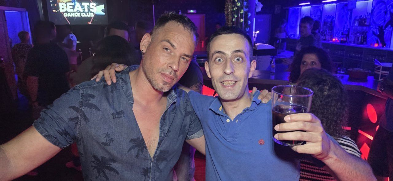 Dos hombres sonrientes en Beats Dance Club durante una fiesta animada.