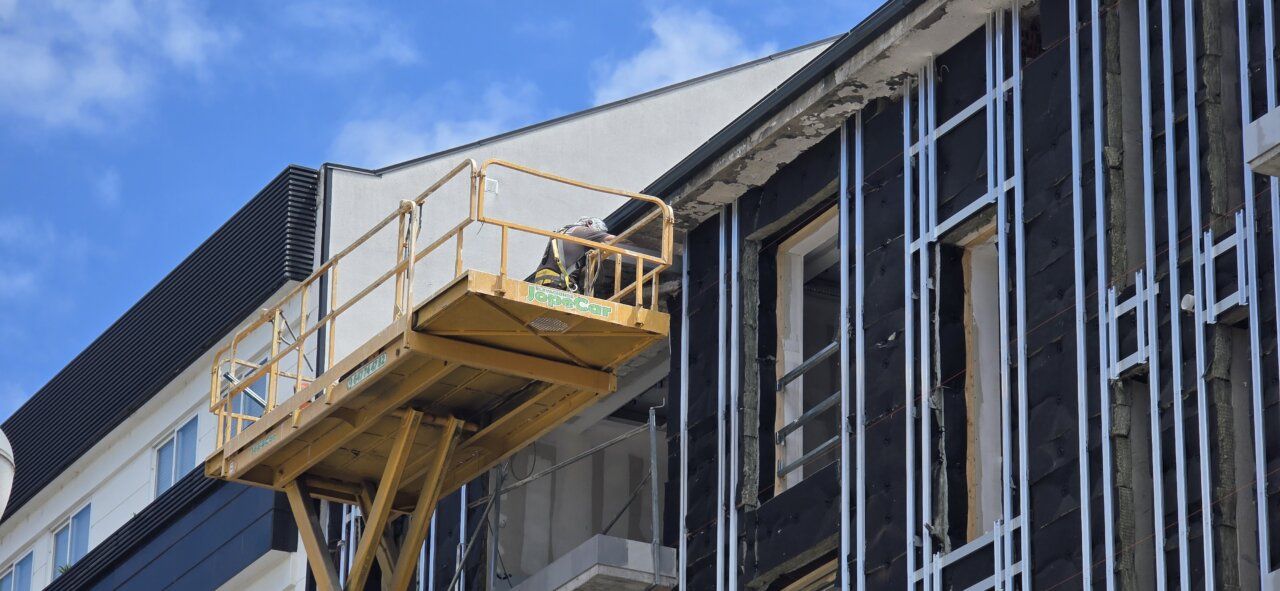 Trabajador en plataforma elevadora realizando labores de construcción