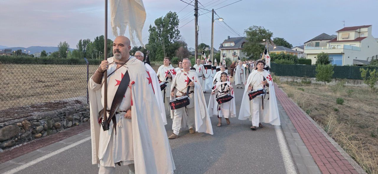 Grupo de personas con capas blancas y cruces rojas en un desfile medieval